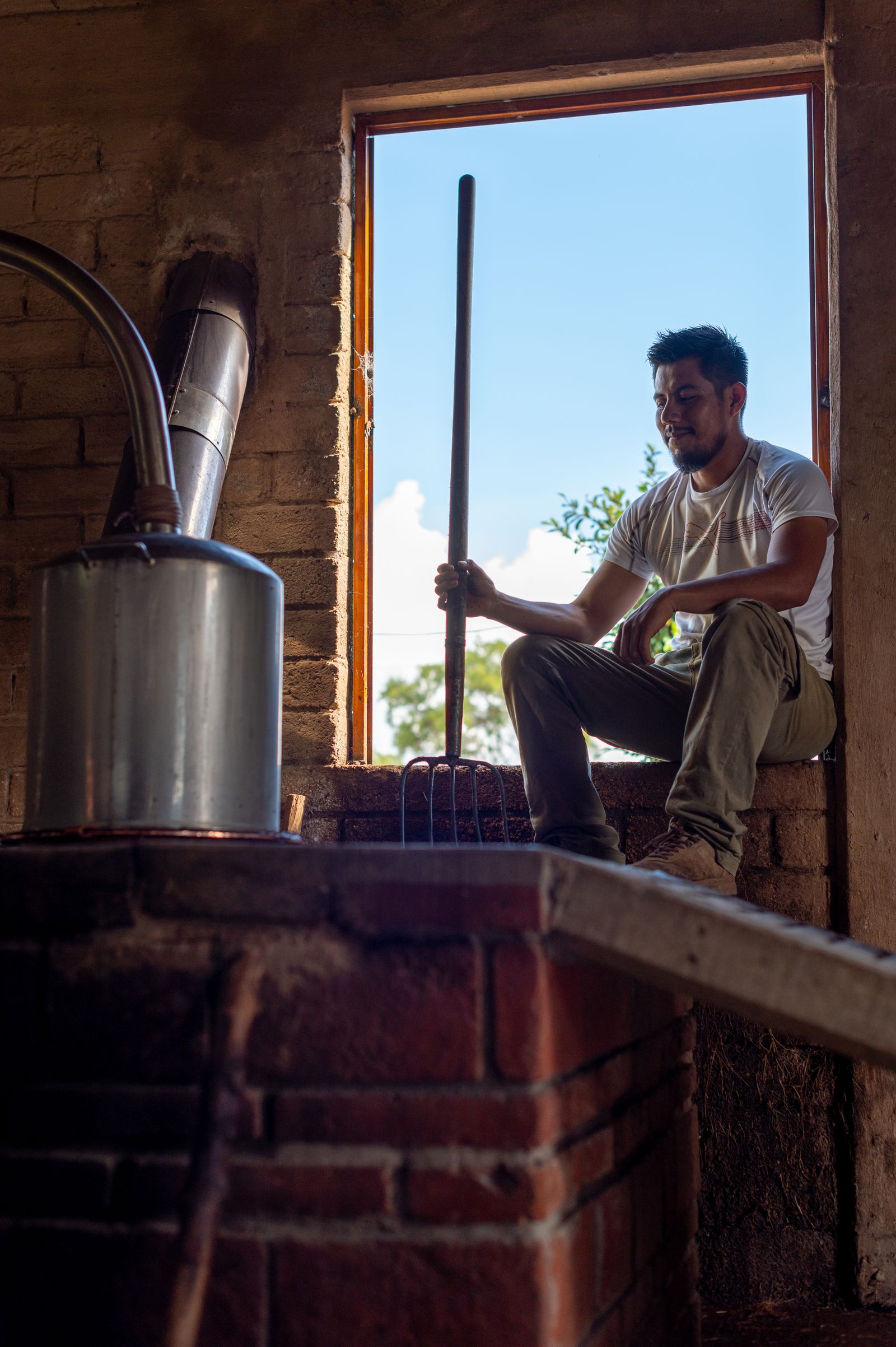 Mezcalero en su palenque, a la luz de la ventana